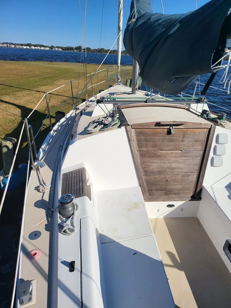 Slide: The Image of 1988 Catalina 30 sailboat docked by the shore under blue sky. - 21