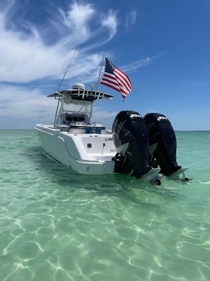 Slide: The Image of 2004 Donzi 35 ZF Open boat with dual engines in clear turquoise water, American flag flying. - 3
