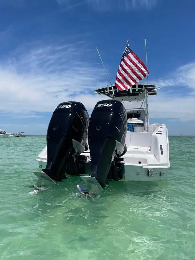 Slide: The Image of 2004 Donzi 35 ZF Open boat with dual engines and American flag on clear water. - 8