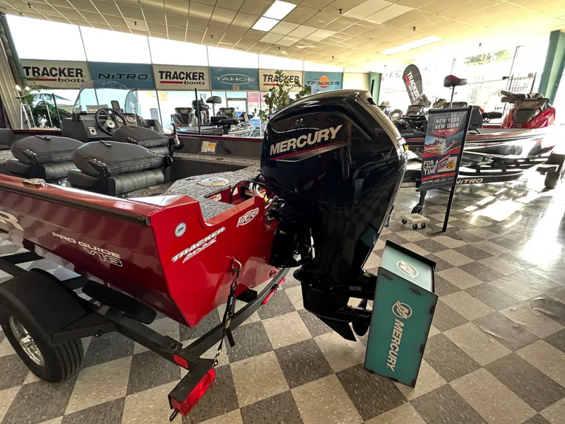 Slide: The Image of 2025 Tracker Pro Guide V-16 SC boat with Mercury engine in showroom display. - 2