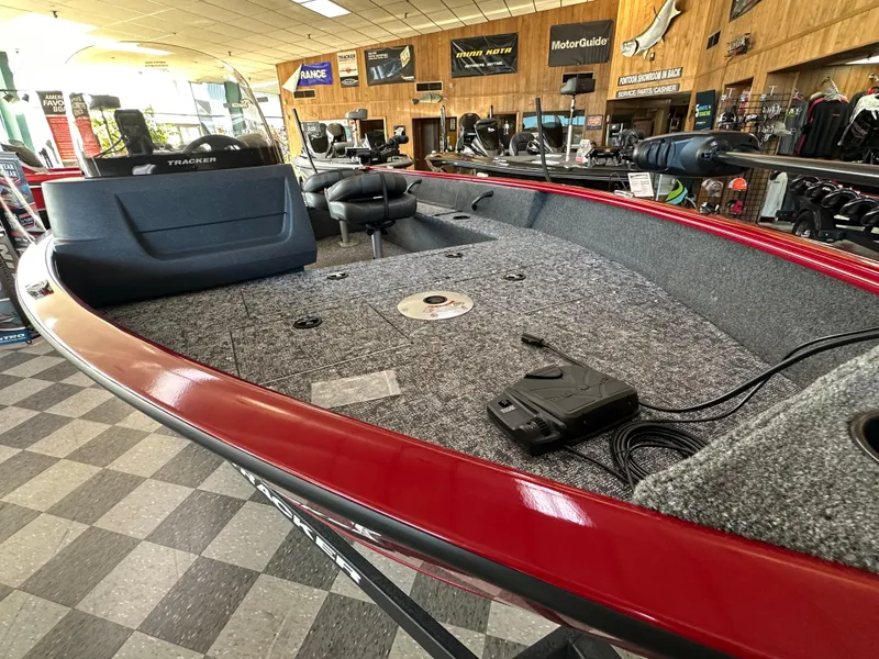 Slide: The Image of 2025 Tracker Pro Guide V-16 SC boat interior with red trim and carpeted deck in showroom. - 3