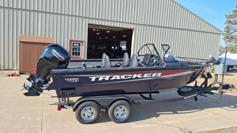 The Image of 2025 Tracker Targa V-18 WT boat on trailer, parked outside a large building. - 0