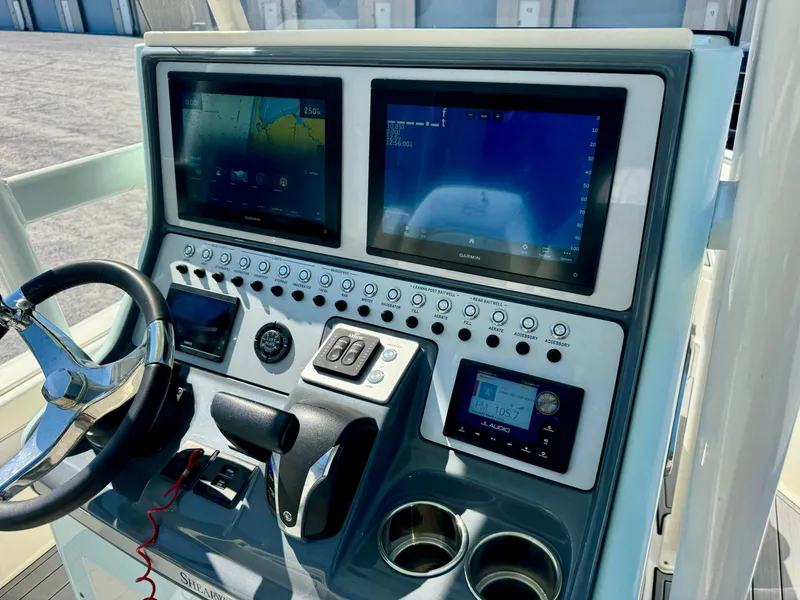 Slide: The Image of ShearWater 260 Carolina Flair 2022 boat dashboard with dual screens and controls. - 13