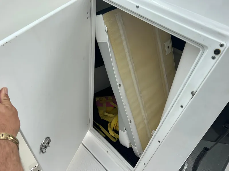 Slide: The Image of 2024 Blackfin 272 DC storage compartment with open door, revealing interior items. - 18