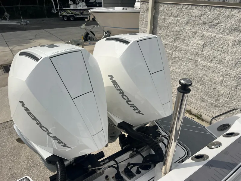 Slide: The Image of Twin Mercury outboard engines on a 2024 Blackfin 272 DC boat, parked near a concrete wall. - 38