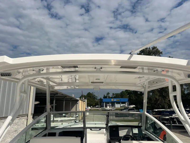 Slide: The Image of 2024 Blackfin 272 DC boat with a sleek white hardtop under a partly cloudy sky. - 41