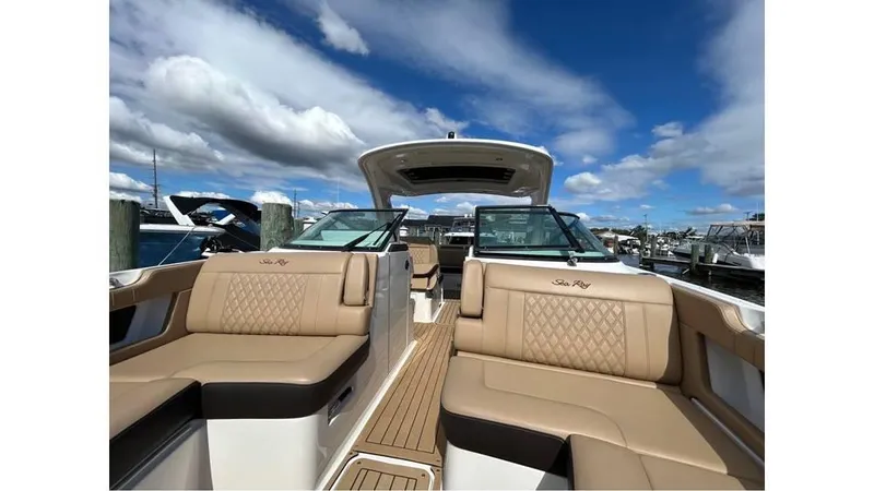 Slide: The Image of 2019 Sea Ray 310 SLX boat with luxurious seating, docked under a blue sky. - 17