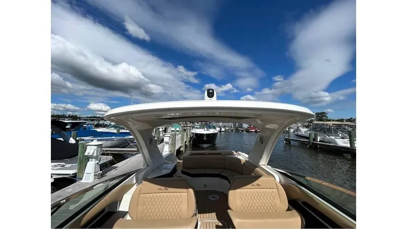 Slide: The Image of 2019 Sea Ray 310 SLX boat interior with tan seating, docked under a blue sky. - 19