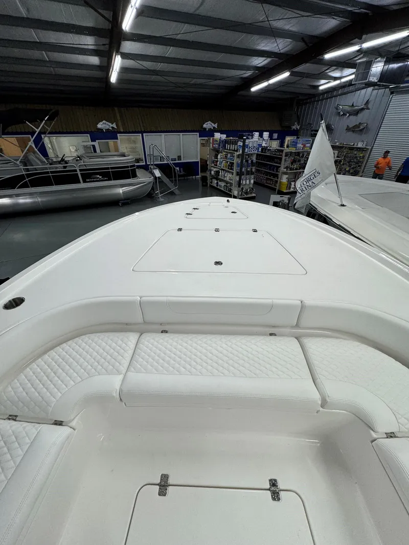 Slide: The Image of 2025 Caymas 281 HB boat interior in showroom, featuring sleek white seating and storage. - 33