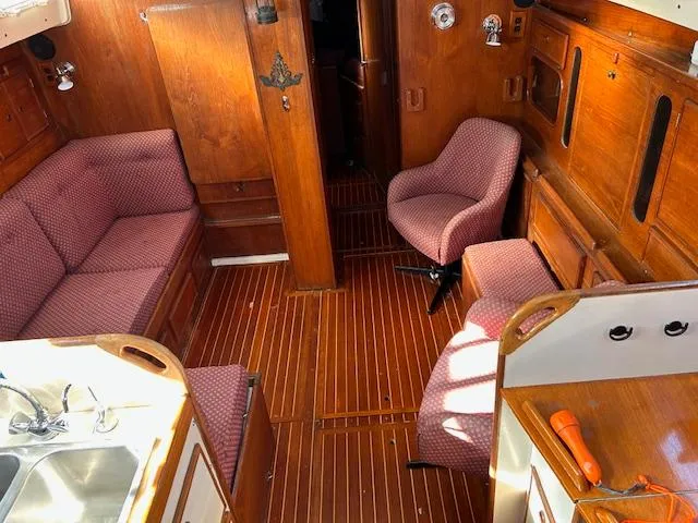 Slide: The Image of Interior of 1984 Whitby 42 Ketch, featuring wood paneling and red upholstered seating. - 18