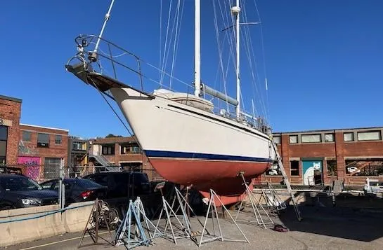 Slide: The Image of 1984 Whitby 42 Ketch sailboat on stands in a shipyard, clear blue sky. - 2