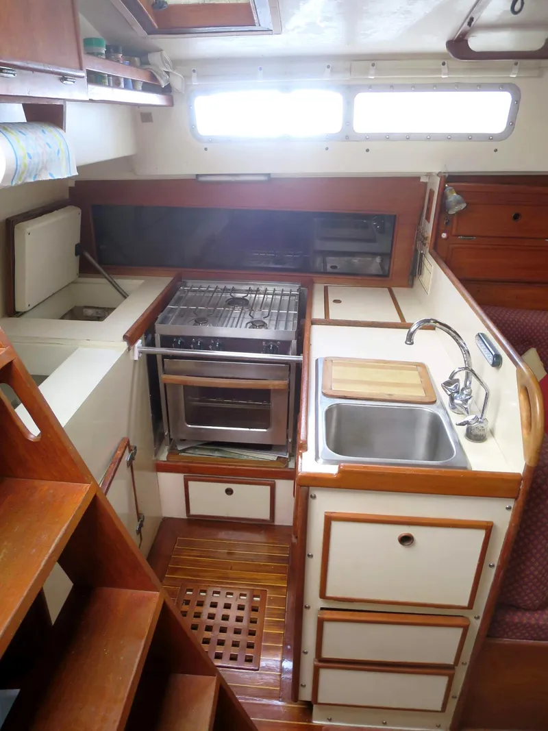 Slide: The Image of Compact kitchen in 1984 Whitby 42 Ketch sailboat with stove, sink, and wooden cabinetry. - 26