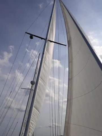 Slide: The Image of 1984 Whitby 42 Ketch sailboat with sails unfurled against a cloudy sky. - 38