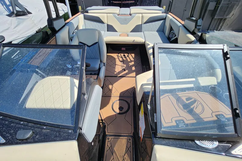 Slide: The Image of 2022 Tigé Z1 boat interior with beige and gray seating, open windshield, and wood-patterned flooring. - 10