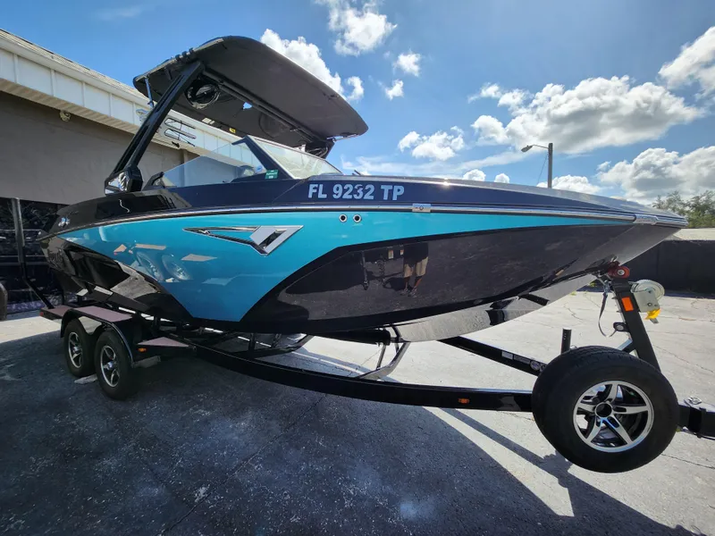 Slide: The Image of 2022 Tigé Z1 boat with blue and black design on a trailer under a sunny sky. - 12