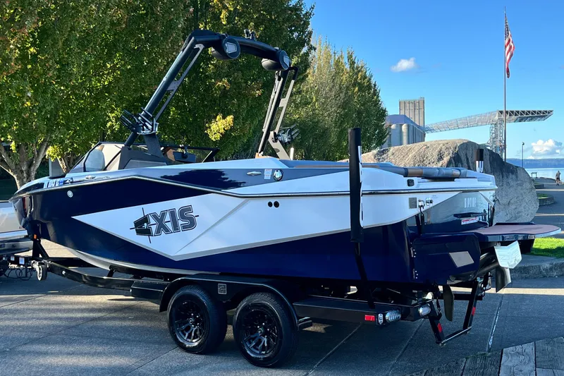 Slide: The Image of 2024 Axis T 220 boat on trailer, parked outdoors near trees and water. - 12