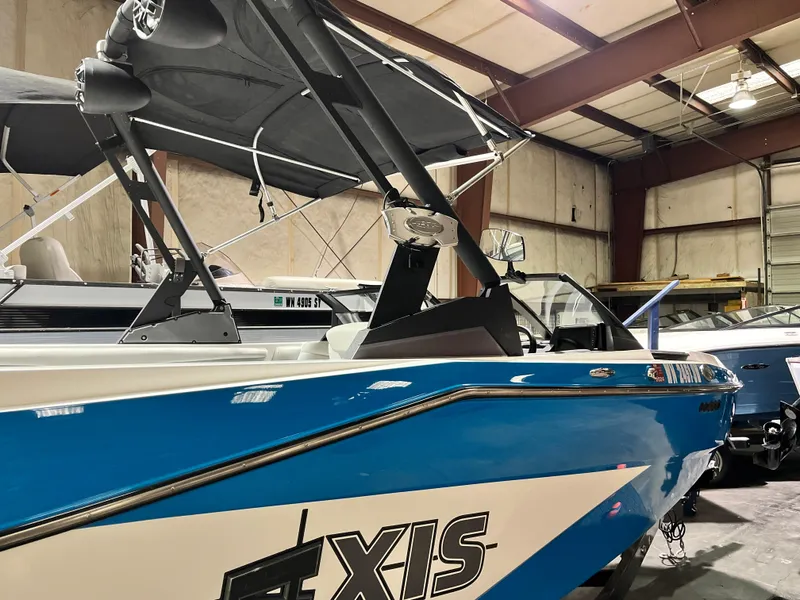 Slide: The Image of 2024 Axis T 220 boat in a warehouse, featuring a sleek blue and white design. - 2