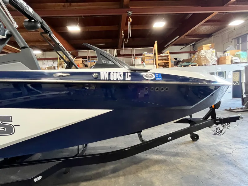 Slide: The Image of 2024 Axis T 220 boat in a garage, blue and white design, on a trailer. - 4