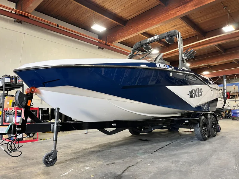 Slide: The Image of 2024 Axis T 220 boat in a garage, blue and white design, on a trailer. - 9