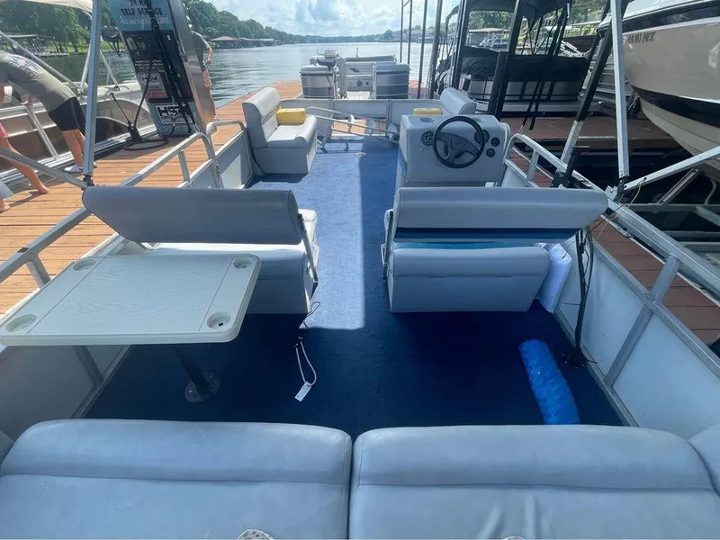 Slide: The Image of 1994 Alumaweld Getaway pontoon boat interior with seating and steering console on a sunny day. - 8