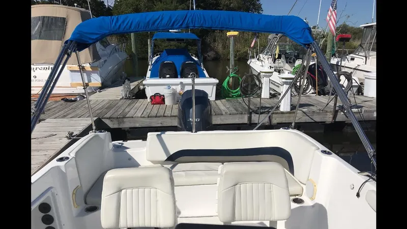 Slide: The Image of 2014 Hurricane SunDeck Sport 231 OB boat docked with blue canopy and white seating. - 1