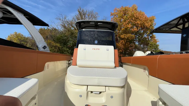 Slide: The Image of 2024 Capoforte FX270 boat interior with tan seating and autumn trees in the background. - 26