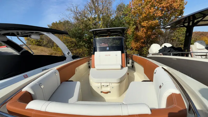 Slide: The Image of 2024 Capoforte FX270 boat interior with white and brown seating, surrounded by trees. - 37