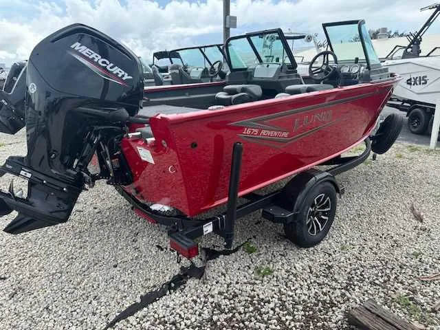 Slide: The Image of 2025 Lund 1675 Adventure Sport boat with Mercury engine, parked on gravel. - 3