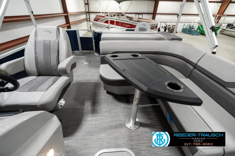 Slide: The Image of 2021 Bennington 22SX pontoon boat interior with seating and table in a showroom. - 14