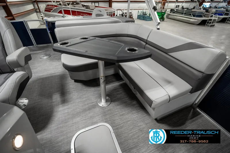 Slide: The Image of 2021 Bennington 22SX boat interior with gray seating and table in showroom. - 25