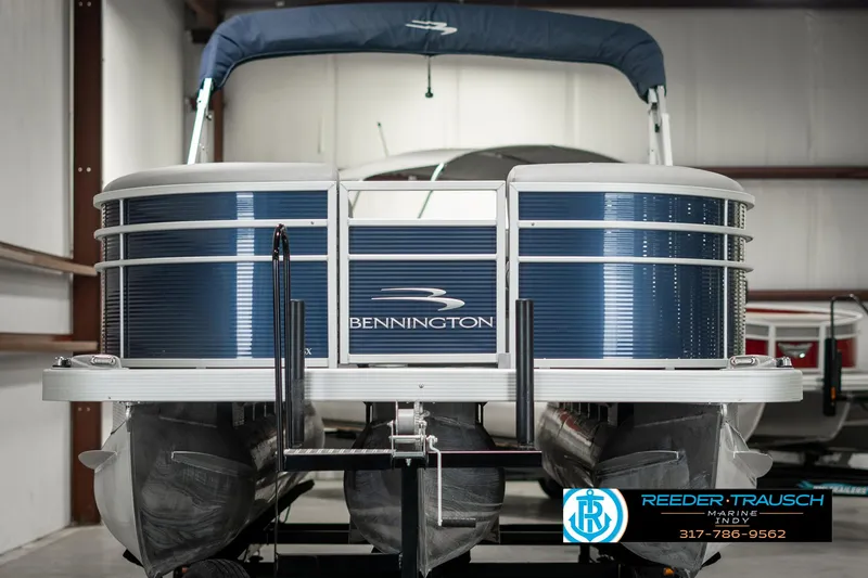 Slide: The Image of 2021 Bennington 22SX pontoon boat in showroom, blue exterior, Reeder-Trausch Marine logo visible. - 8
