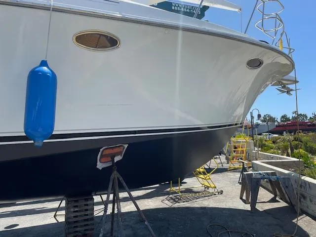Slide: The Image of 1990 Trojan 40 Sport Fisherman boat on dry dock, featuring blue hull and white upper deck. - 20