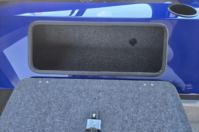 Slide: The Image of Open storage compartment in 2024 Spartan 240 Maximus boat, featuring blue exterior and carpeted interior. - 32