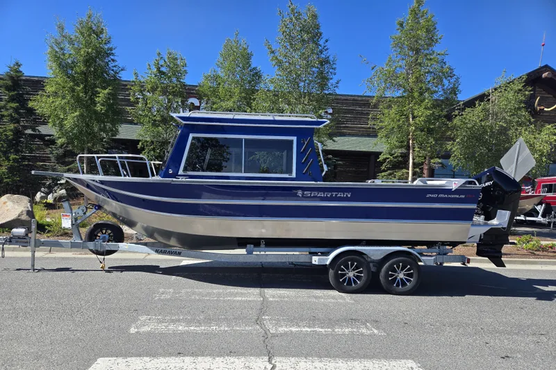 The Image of 2024 Spartan 240 Maximus boat on trailer, parked outdoors with trees in background. - 0