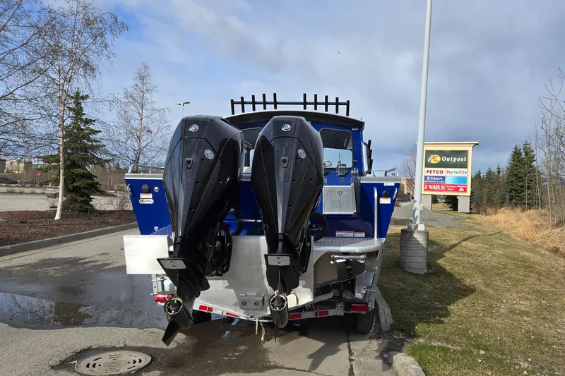 Slide: The Image of 2024 Spartan 26 Maximus Pro XL boat with dual outboard motors in a parking lot. - 35