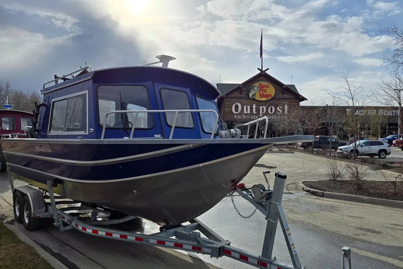 Slide: The Image of 2024 Spartan 26 Maximus Pro XL boat with dual outboard motors, parked on a street. - 6