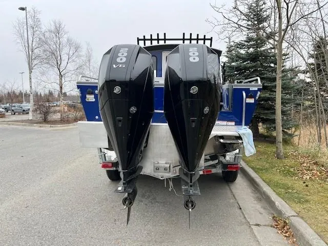 Slide: The Image of 2024 Spartan 26 Maximus Pro XL boat, spacious deck, blue cabin, parked near road. - 8