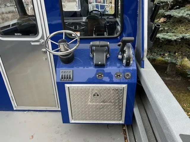 Slide: The Image of 2024 Spartan 26 Maximus Pro XL boat cockpit with blue exterior and steering controls. - 9