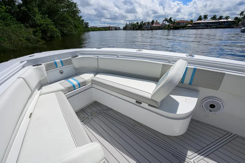 Slide: The Image of 2023 Powerplay Powerboats 30 RumRunner interior with white seating, blue accents, and scenic water view. - 16