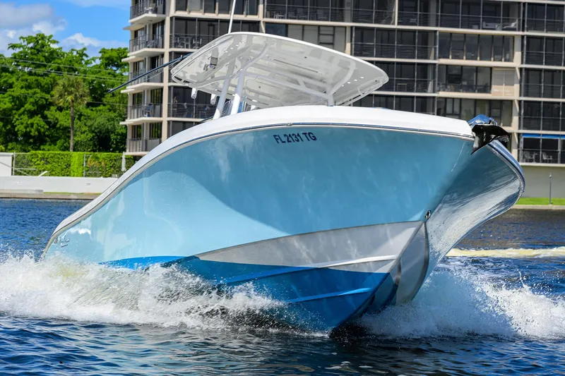 Slide: The Image of 2023 Powerplay Powerboats 30 RumRunner cruising on water near modern buildings. - 8