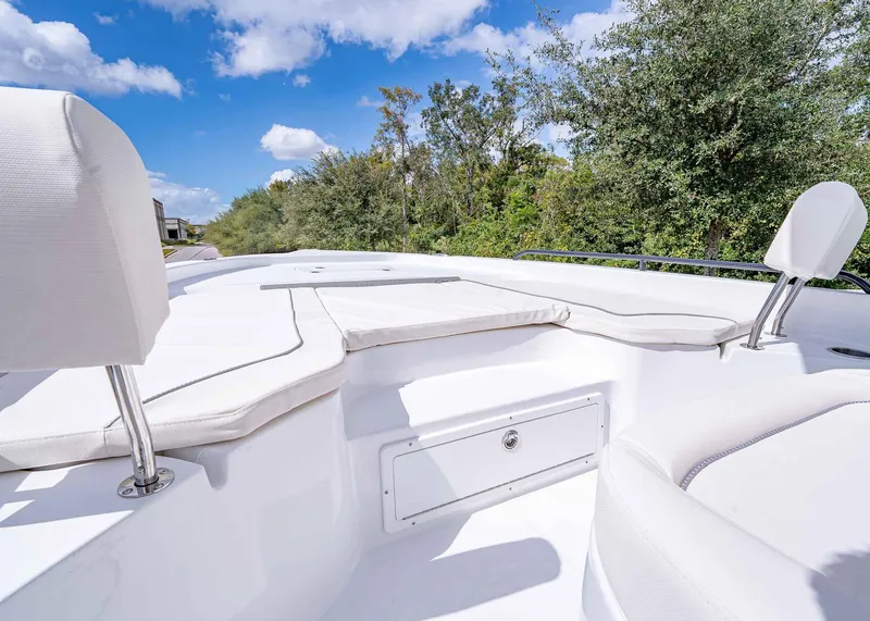 Slide: The Image of 2025 Sea Hunt BX 25 FS boat interior with white seating and storage, surrounded by greenery. - 18