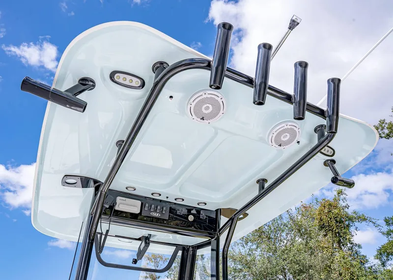 Slide: The Image of 2025 Sea Hunt BX 25 FS boat T-top with rod holders and speakers against blue sky. - 9