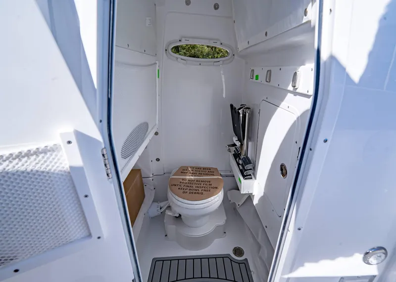 Slide: The Image of 2025 Sea Hunt Ultra 255 SE boat interior bathroom with toilet and storage. - 18