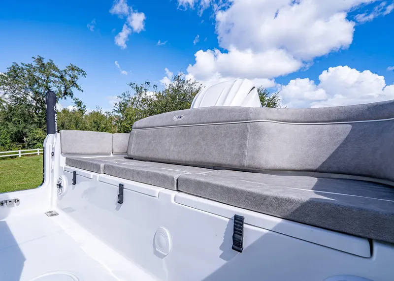 Slide: The Image of 2025 Sea Hunt Ultra 255 SE boat interior with cushioned seating under a blue sky. - 17