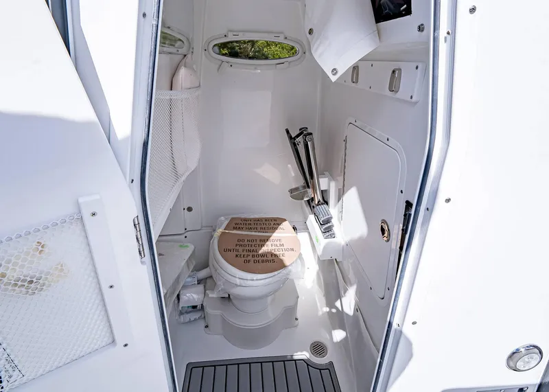 Slide: The Image of Interior of 2025 Sea Hunt Ultra 255 SE boat bathroom with toilet and storage. - 18