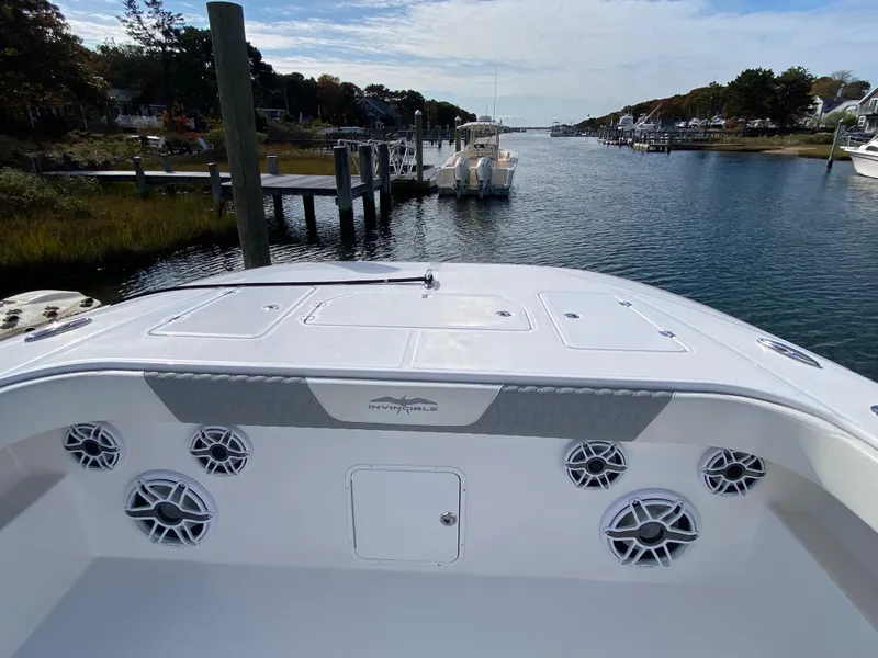 Slide: The Image of 2023 Invincible 46 Catamaran Plus Quad Axle Trailer on water, showcasing deck and speakers. - 3