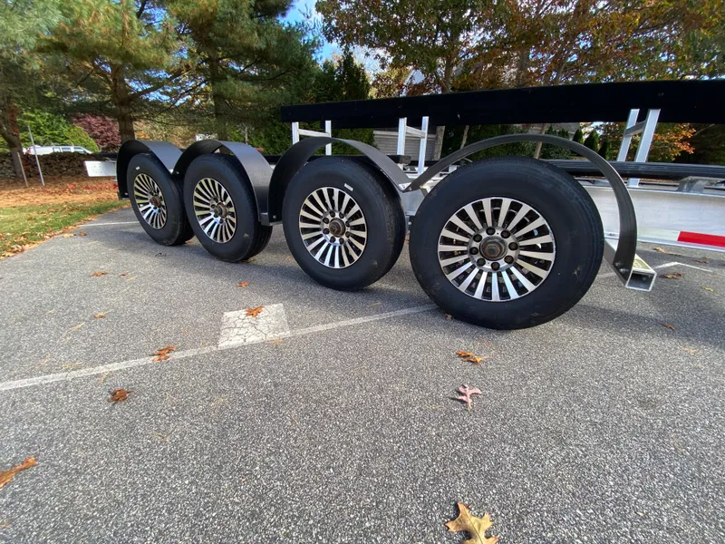 Slide: The Image of 2023 Invincible 46 Catamaran Plus Quad Axle Trailer with sleek wheels in a parking lot. - 31