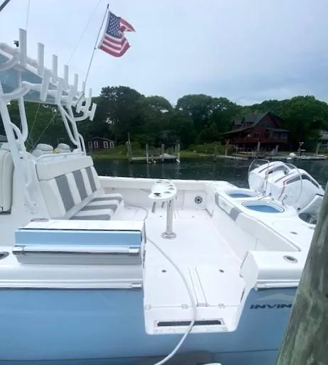 Slide: The Image of 2023 Invincible 46 Catamaran with Quad Axle Trailer, docked, featuring spacious seating and American flag. - 27