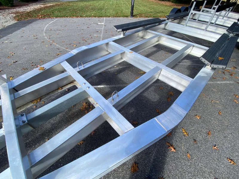 Slide: The Image of 2023 Invincible 46 Catamaran Plus Quad Axle Trailer on pavement, showcasing sturdy metal frame. - 32