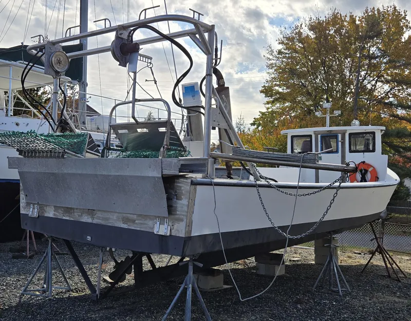 Slide: The Image of 1985 Kinnamon Pilot House Chesapeake Deadrise boat on stands, with fishing equipment, outdoors. - 27